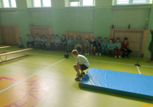 Uczeń kończy przewrót w przód.
