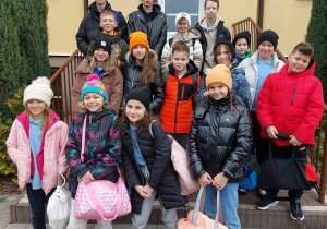 Uczniowie biorący udział w zawodach pozują do zdjęcia na tle budynku szkoły.