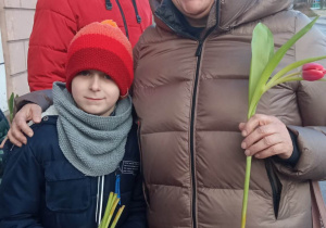 Uczeń wręcza kwiaty mieszkańce Brzezin.