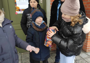 Uczniowie wrzucają pieniądze do puszki.