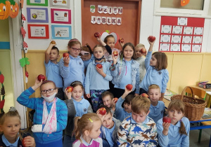Uczniowie pozują do zdjęcia pokazując otrzymane jabłka