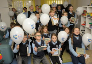 Uczniowie klasy 3 b pozują do zdjęcia z balonami i książkami