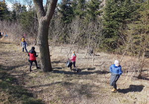 Uczniowie spacerując po lesie zbierają napotkane śmieci