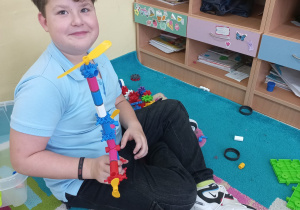 Uczeń prezentuje zbudowaną przez siebie wieżę z klocków.