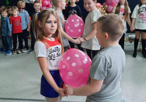Uczniowie tańczą w parach z balonami.