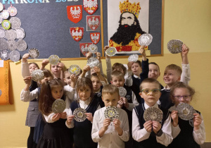 Uczniowie klasy II prezentują wykonane przez siebie monety.