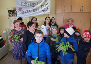 Uczniowie wręczają kwiaty pracownicom DPS-u.