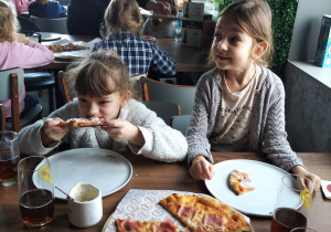Dzieci jedzą wykonane przez siebie pizze.