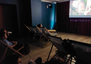 Uczniowie oglądają film na dużym ekranie.