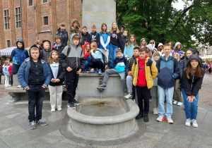 Uczniowie pozują do pamiątkowego zdjęcia pod pomnikiem Mikołaja Kopernika.