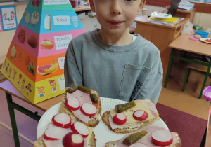 Uczeń prezentuje zrobione przez siebie kanapki.