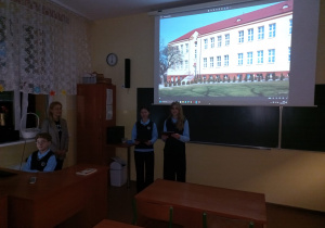 Nauczyciel wraz uczniami prezentuje historię szkoły.