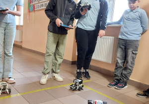 Uczniowie sterują robotami.