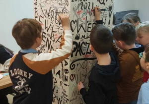 Uczniowie podpisują się na pamiątkowej ściance.